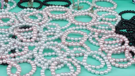 colorful pearl bracelets displayed on turquoise surface