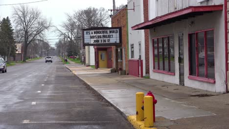 a main street in small town america with small movie theater saying its a wonderful world