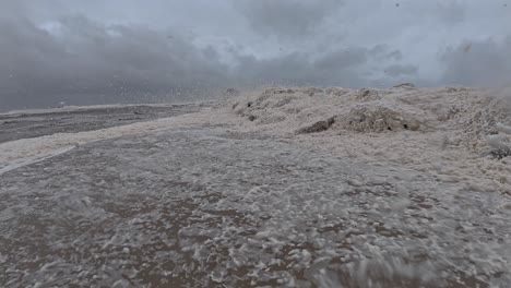 currumbin beach covered in spumes with wind blowing during cyclone alfred in queensland, australia. static shot