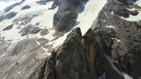 Jagged-snow-capped-mountain-peaks-on-sunny-summer-day-in-Italian-Dolomite,-aerial