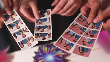 close up of a group of friends having fun looking at prints from photo booth with props 6