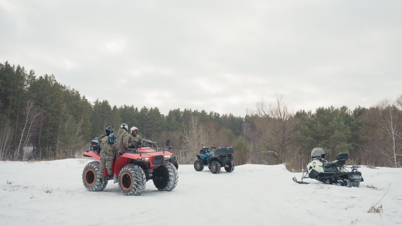 Le macchine attendono al margine dei pini, tese in silenzio. Motori che rombano sulla neve mentre la prontezza dei piloti aumenta. Catturando un momento intenso di motori di ATV che rombano nella quiete invernale con anticipazione.