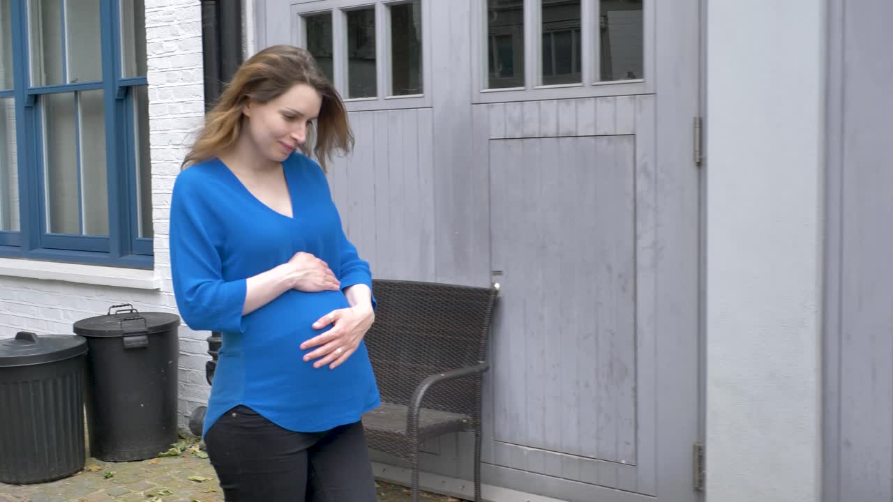 Happy pregnant woman walking down street in London