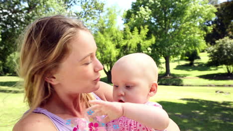 glückliche mutter spielt mit ihrem baby im park