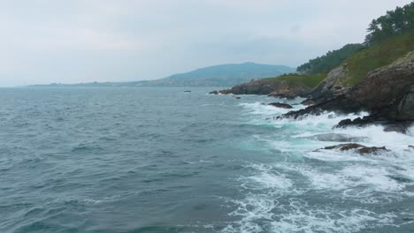 Blue-Ocean-Water-With-Smooth-Waves-Under-High-Mountains-In-Monteferro,-Vigo,-Galicia,-Spain