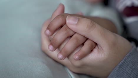 an individual gently holds the hand of a young child, illustrating the profound bond of togetherness and the nurturing support within a family unit