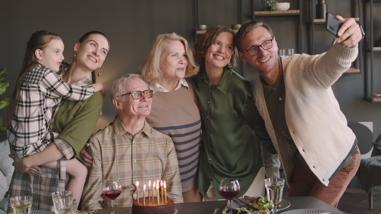 집에서 생일 파티를 하는 동안 셀카 사진을 찍는 행복한 노인과 그의 다세대 가족