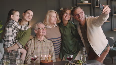 happy senior man and his multigenerational family taking a selfie photo during his birthday party at home