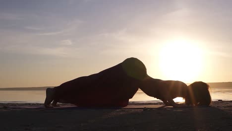 Wunderschöne-Aufnahmen-Am-Strand-Bei-Sonnenuntergang,-Frau-Macht-Yoga-Asanas-Auf-Einer-Matte,-Rückbeuge,-Urdhva-Mukha-Shvansana.-Zeitlupe