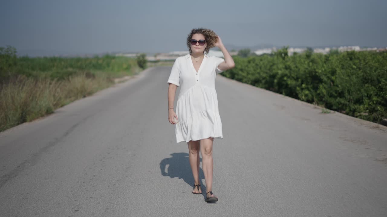Donna che cammina su una strada di campagna in abito bianco
