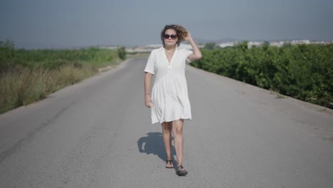 woman walking on a country road in a white dress