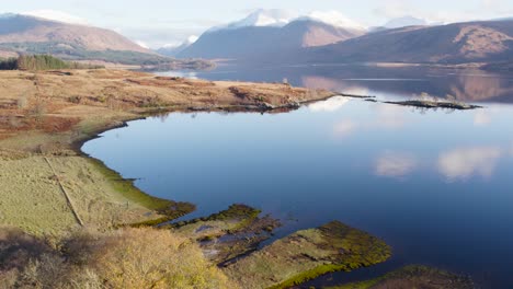 在蘇格蘭高地的洛克埃蒂夫 (loch etive) 岸邊,在冬天,有雪山,樹木,原生森林和靜止的反射水