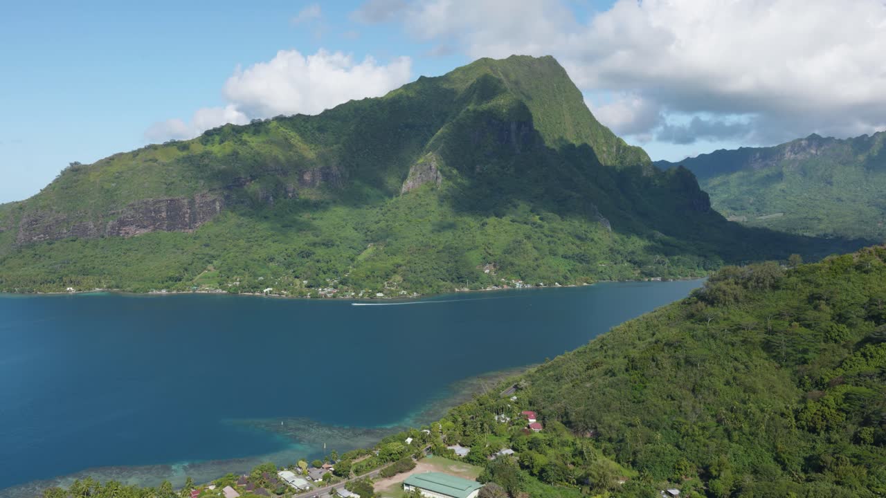 View of mountains and the ocean on a sunny day in a small green tropical pacific island from Magic Mountain, Moorea, French Polynesia.