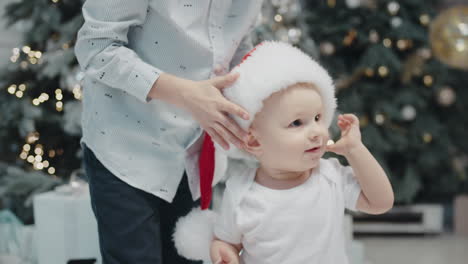 little boy putting off santa hat in living room. elder brother wearing xmas hat