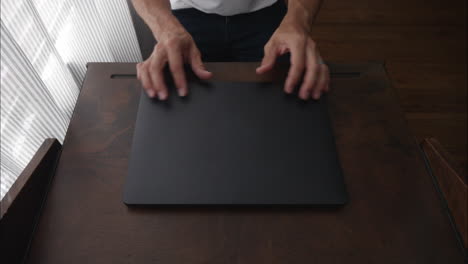 Employee working from home types, closes computer, and walks away from modern desk