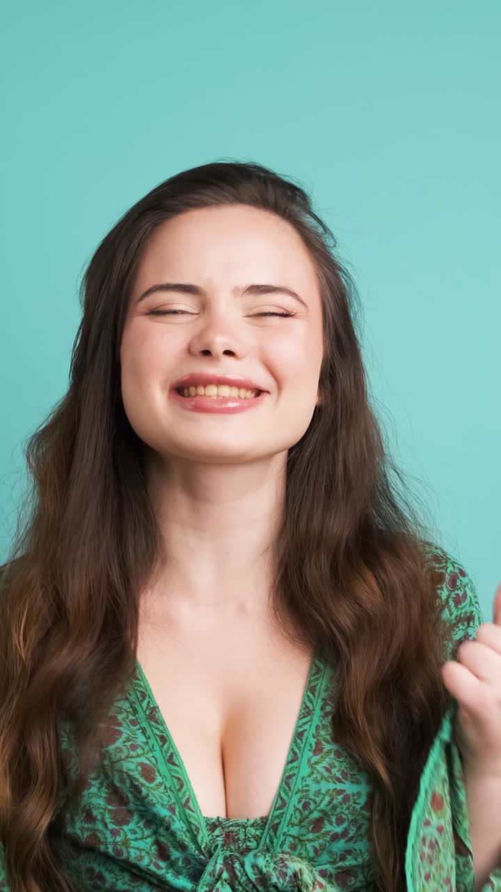Successful young woman clenching fists in blue studio