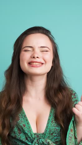 successful young woman clenching fists in blue studio