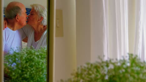 caucasian senior couple kissing each other in bedroom at comfortable home 4k