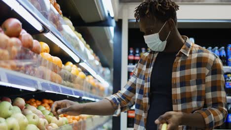 Hombre-Afroamericano-De-Pie-En-El-Supermercado-Poniendo-Manzanas-En-La-Cesta-De-La-Compra.