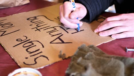 obdachlose frauen basteln ein pappschild mit der aufschrift „alleinerziehende mutter, alles hilft, gott segne“