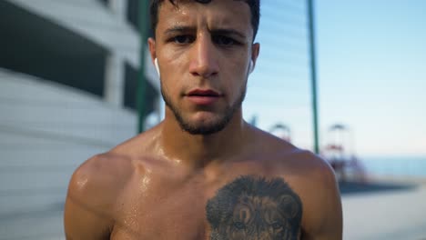 hombre atleta sudoroso con tatuaje de león, concepto de cruz en forma