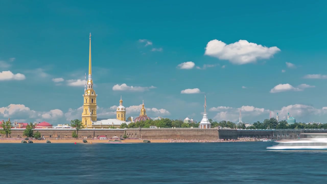 Neva-floden flankeret af Peter og Paul-fæstningen i Sankt Petersborg, Rusland, vist i denne timelapse. Det ikoniske vartegn står højt mod den dramatiske baggrund af en blå, skyet himmel.