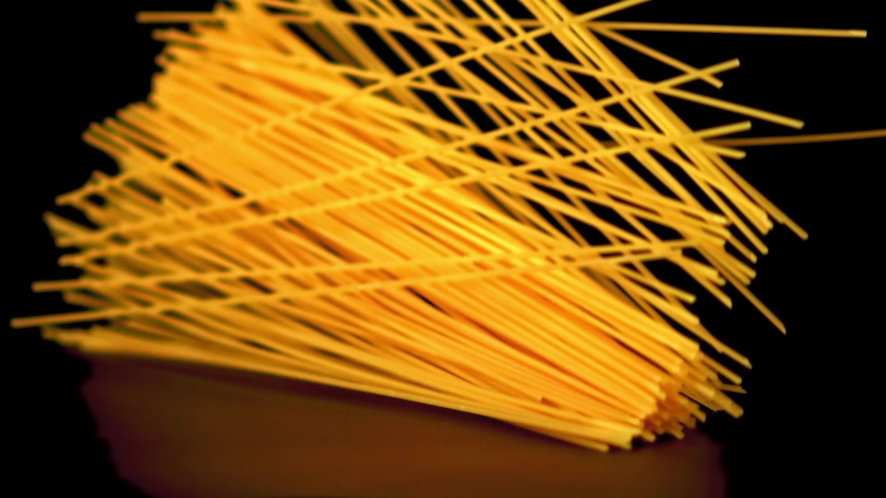 Spaghetti secchi che cadono al rallentatore su sfondo nero