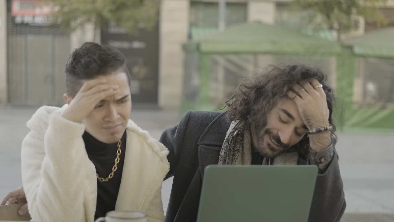 Two men using a laptop outdoors