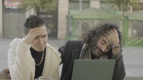 two men using a laptop outdoors