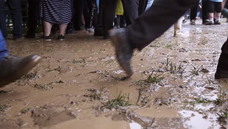 peoples legs seen walking through muddy puddles in wet footwear after downpour of rain at summer festival