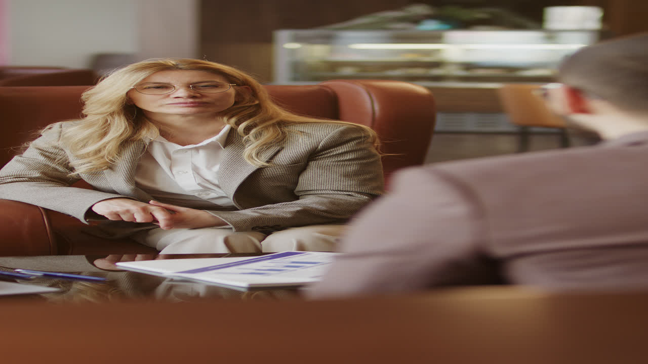 Kvindelig leder diskuterer forretningsplan med kollega i hotellobbyen