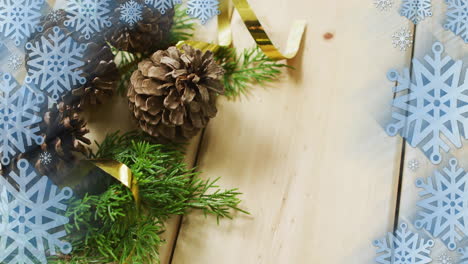 animation of christmas decorations with copy space over snowflakes on wooden background
