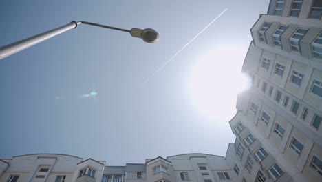 view of sky with airplane leaving white contrail. view up to lamp post.