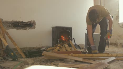 Joven-Cortando-Palos-Con-Hacha-Frente-A-La-Estufa-Mientras-Renueva-La-Casa