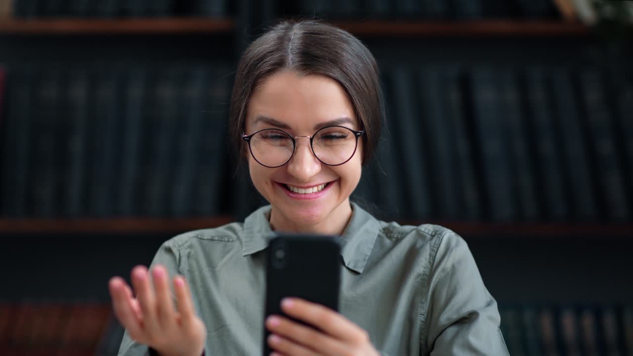 Overjoyed student business woman received surprise message good news smartphone at library