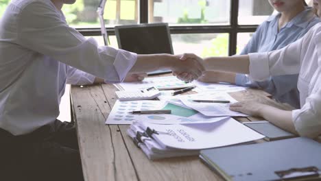 young asian business people shaking hands in the office. finishing successful meeting. three persons.