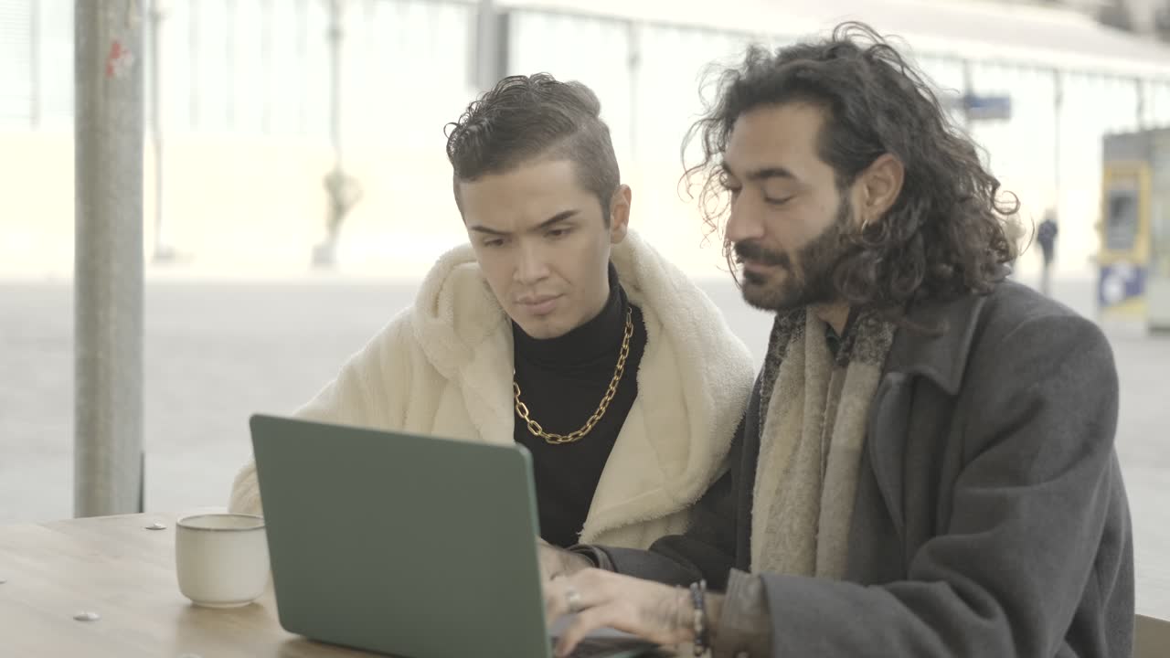 Two men using a laptop in a cafe