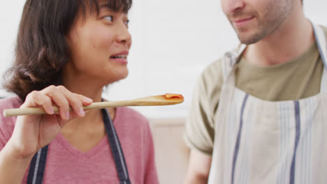 video de una pareja feliz y diversa preparando una comida juntos, probando un plato