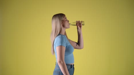 mujer atractiva bebe agua de una botella de vidrio, perfil lateral, toma de estudio