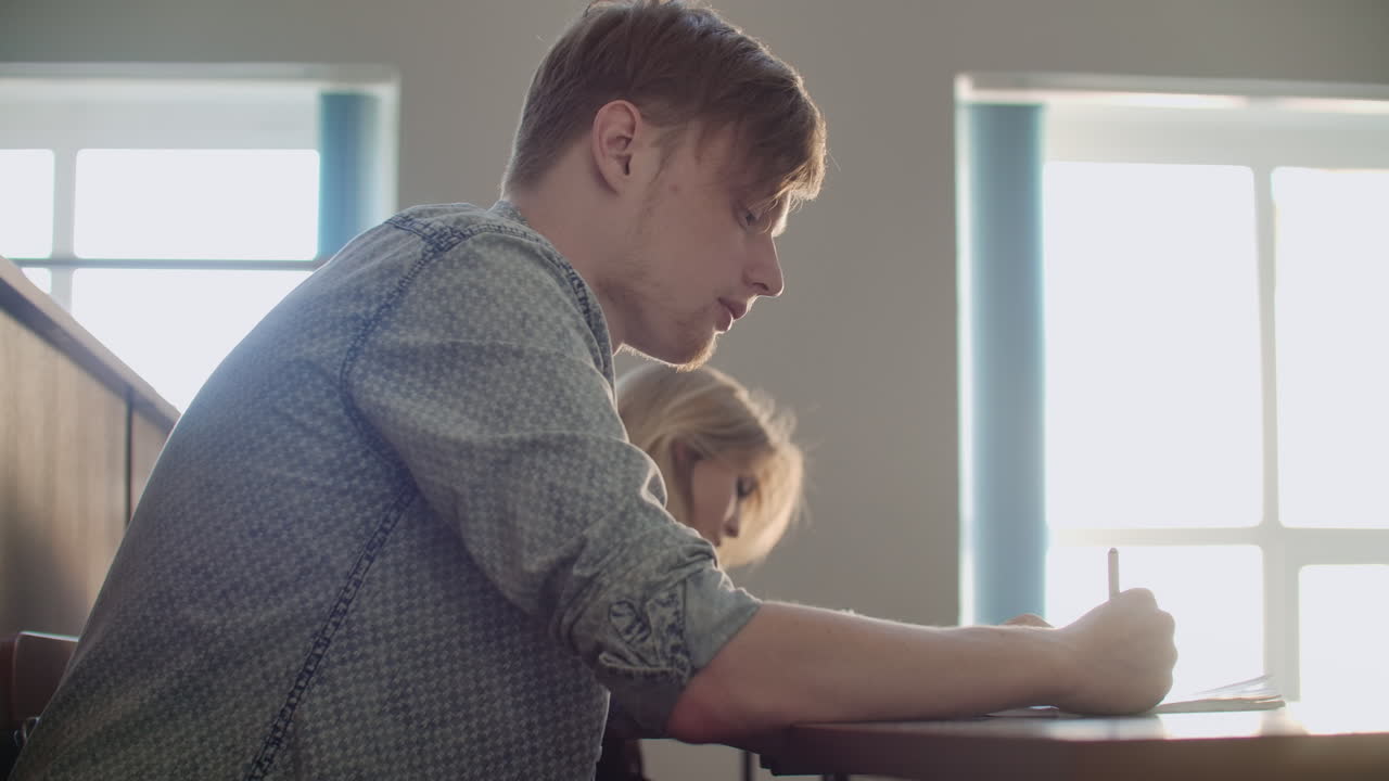 카메라는 학생들이 대학이나 대학의 큰 교실에서 교수들을 위해 노트북과 노트북으로 강의를 쓰는 관객을 통해 움직입니다.