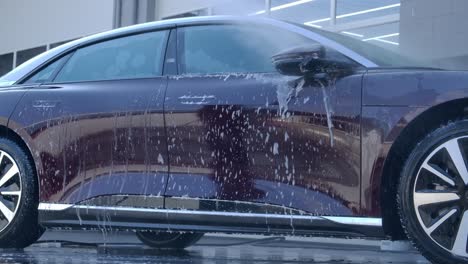 rinsing car - spraying car covered in soap bubbles with water