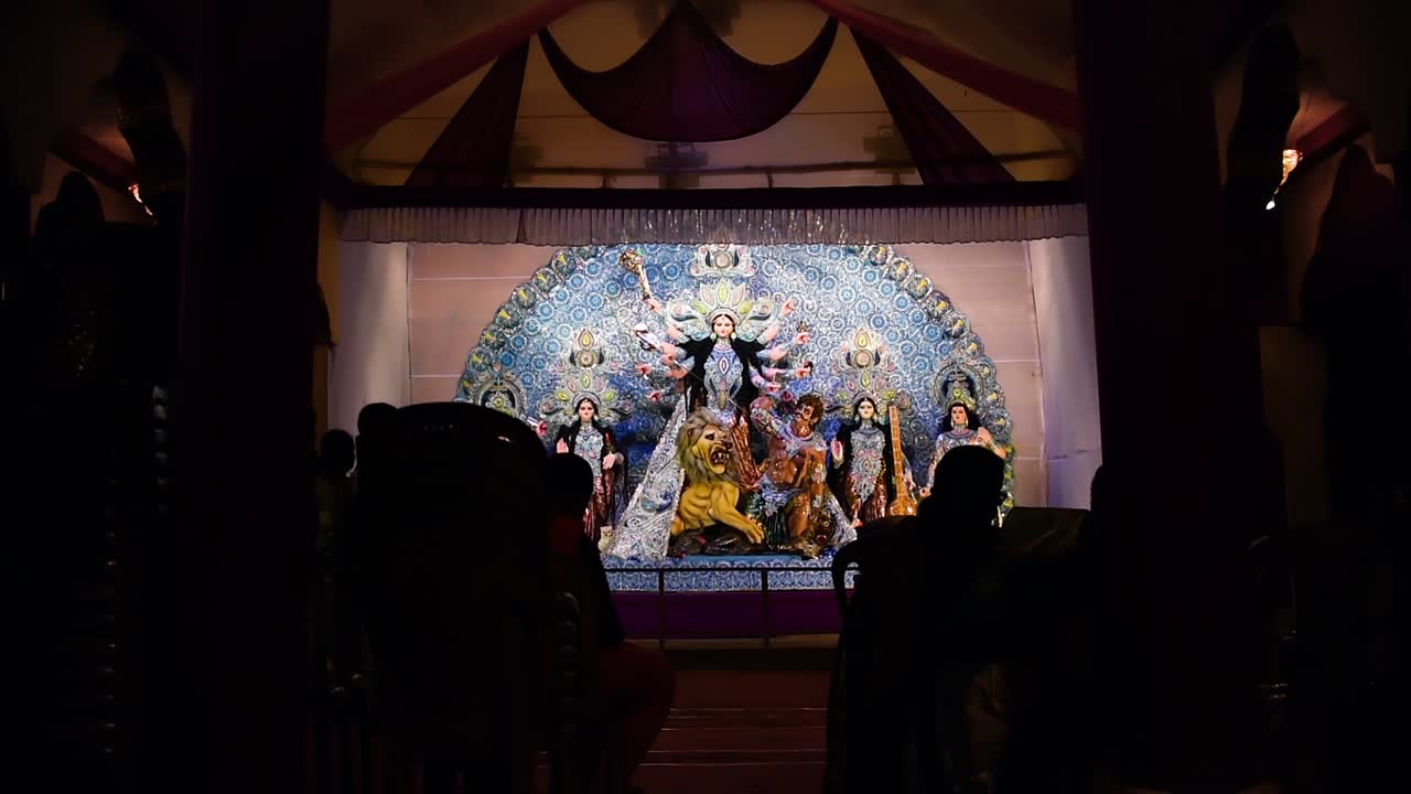 escultura de dioses y diosas indios durga en pandal y silueta de personas disfrutando del festival durga puja por la noche
