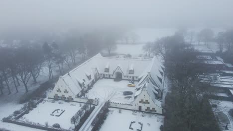 aerial orbit of beautiful old farmhouse in a snow covered rural landscape