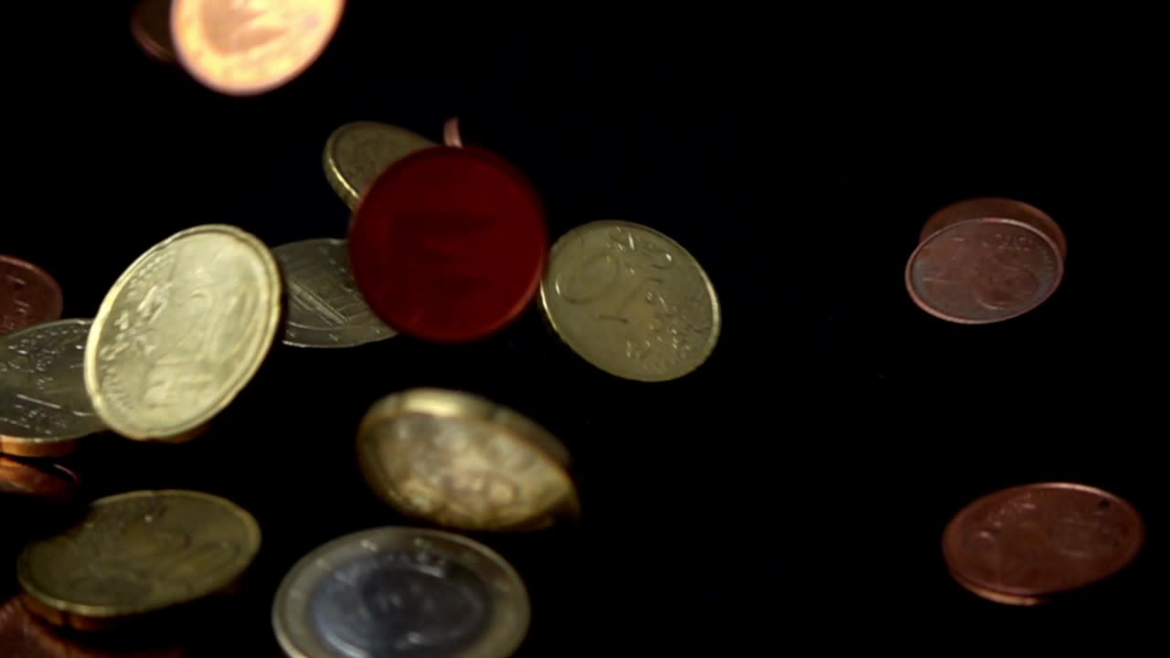 Coins fall on a black background. Slow motion