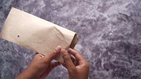 hands holding a brown envelope with money inside