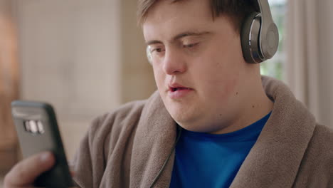 happy boy with down syndrome using smartphone listening to music watching entertainment online enjoying mobile phone communication relaxing at home