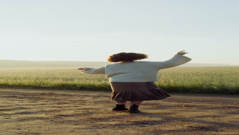 woman dancing in a wheat field at sunrise