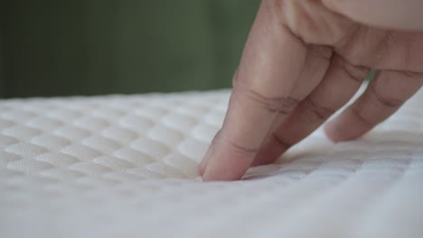 close up of hand touching a soft white mattress