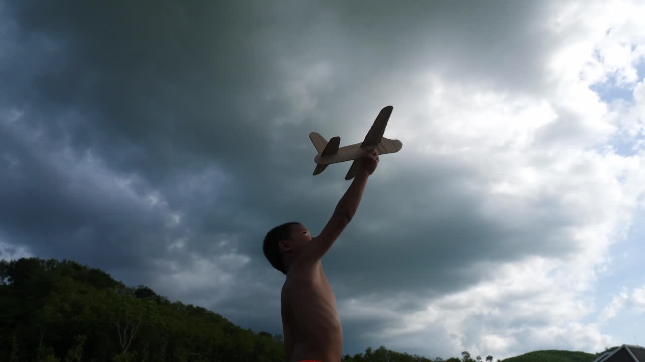 Boy playing with a paper airplane under stormy clouds