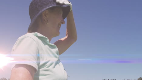 animación de rastros de luz sobre una mujer caucásica mayor jugando al golf en un campo de golf